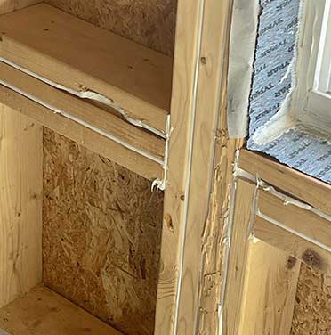 An image captures the air-sealed framework of a new construction project, highlighting the meticulous sealing around wooden beams and joints to optimize energy efficiency and minimize air infiltration