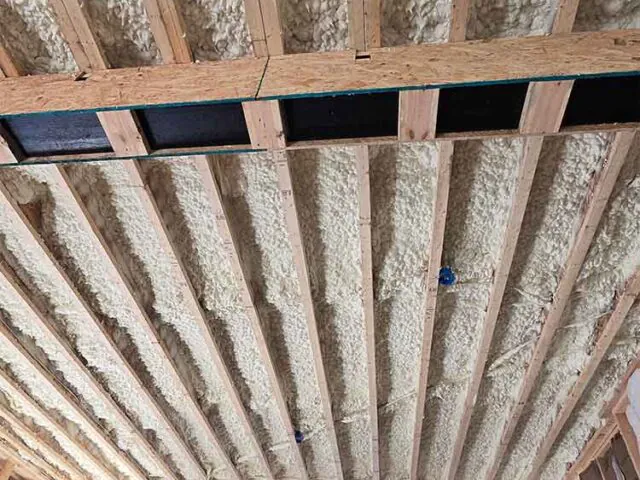 Open cell spray foam insulation applied to garage ceiling joists.