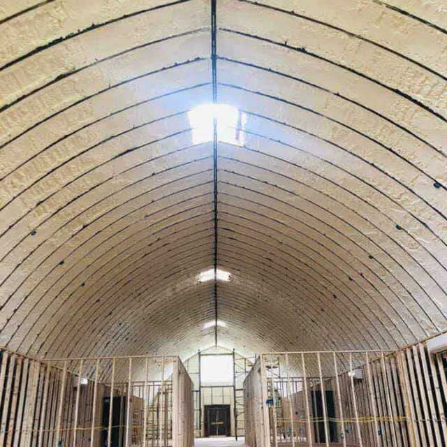 Open-cell spray foam insulation in barndominium wedding venue under construction.
