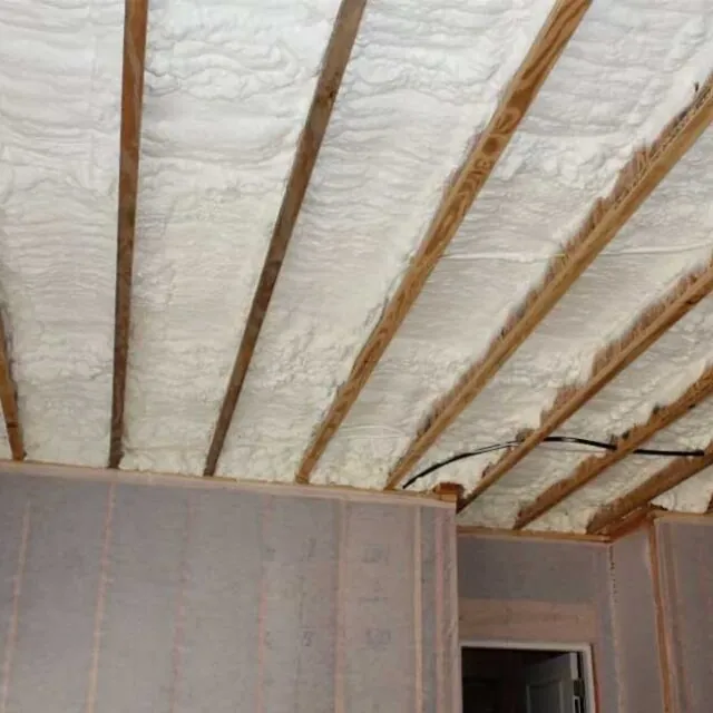 Spray foam insulation in a ceiling with exposed beams.