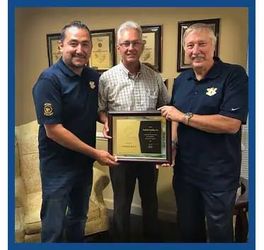 A group of smiling team members from Southland Insulators proudly display an award, celebrating their achievement and teamwork in providing excellent insulation services.