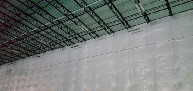 Vinyl-faced fiberglass insulation along wall and ceiling line in tilt-up building.
