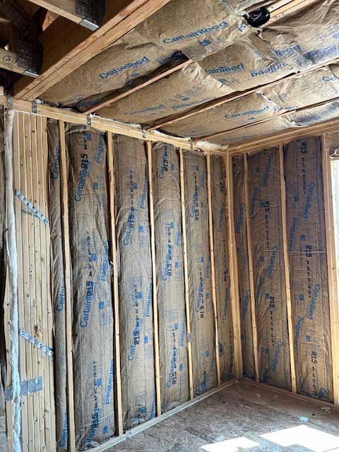 Fiberglass batt insulation installed in wall and ceiling of residential construction.