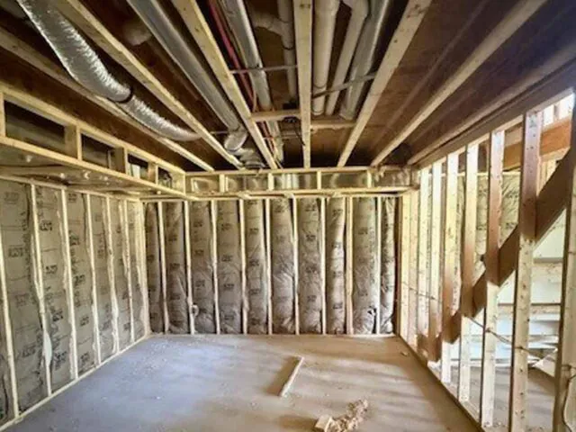 Fiberglass batt insulation installed in basement wall studs during new home construction in Virginia.