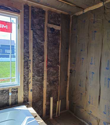 A wide view of neatly arranged pink fiberglass insulation batts is shown, illustrating their uniform thickness and texture, emphasizing their role in energy efficiency and sound absorption in construction projects.