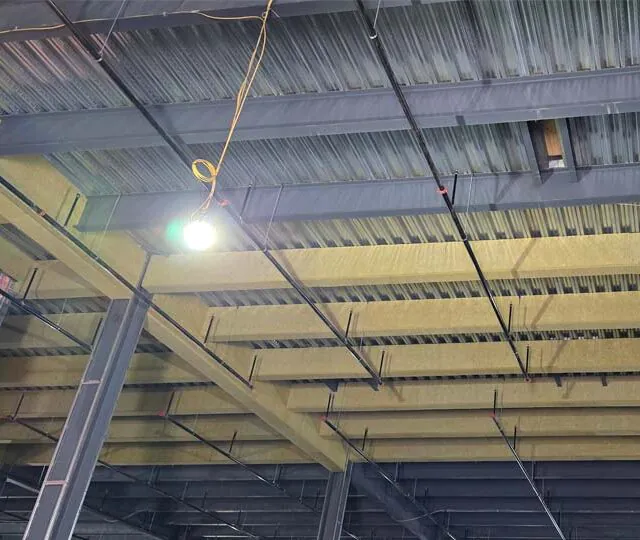 Fireproofing installed across steel roof beams and metal deck at a data center. Fireproofing installed across steel roof beams and metal deck at a data center.