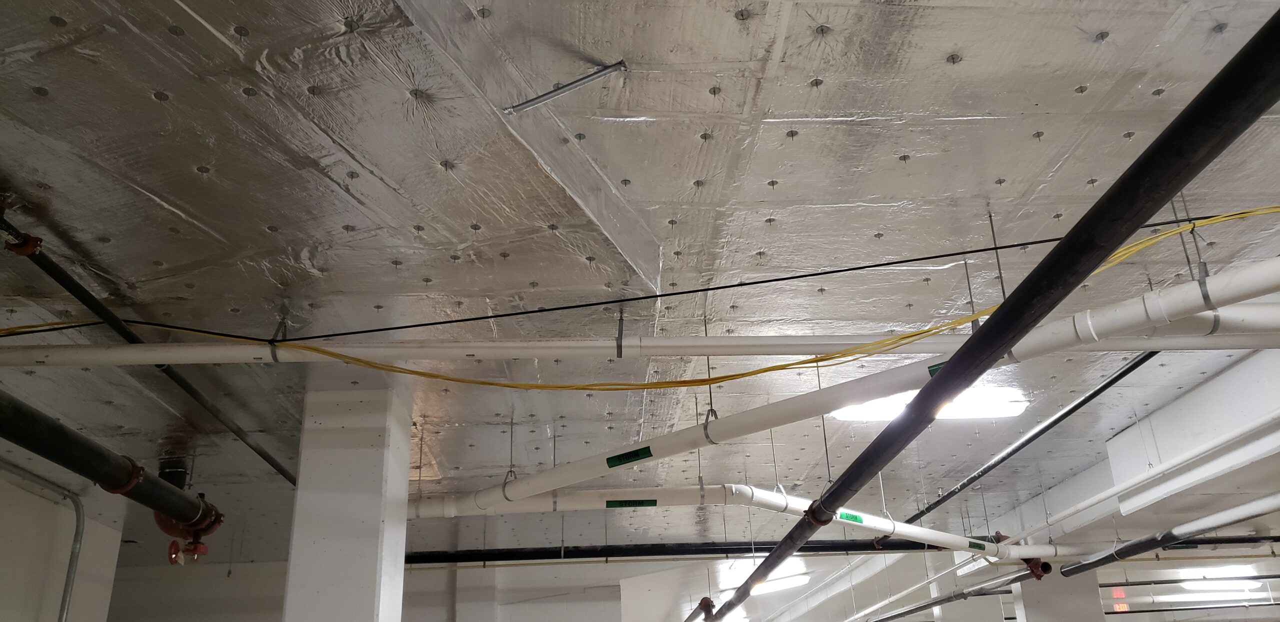 Parking garage ceiling insulated with rigid foam board.