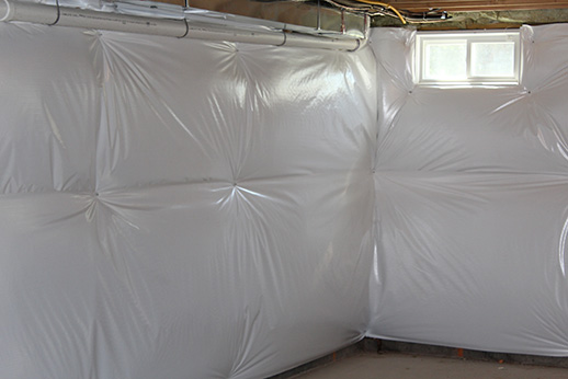 Southland Insulators basement wall insulation with poly vapor barrier installed in corner near basement window in Northern Virginia.