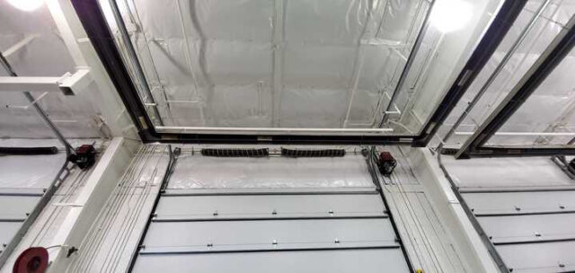 White vinyl PSK faced insulation above overhead door tracks in metal building.