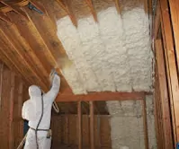 Worker installing spray foam insulation in walls and ceiling.