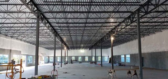 Vinyl-faced fiberglass insulation installed in tilt-up commercial building near workbench area.